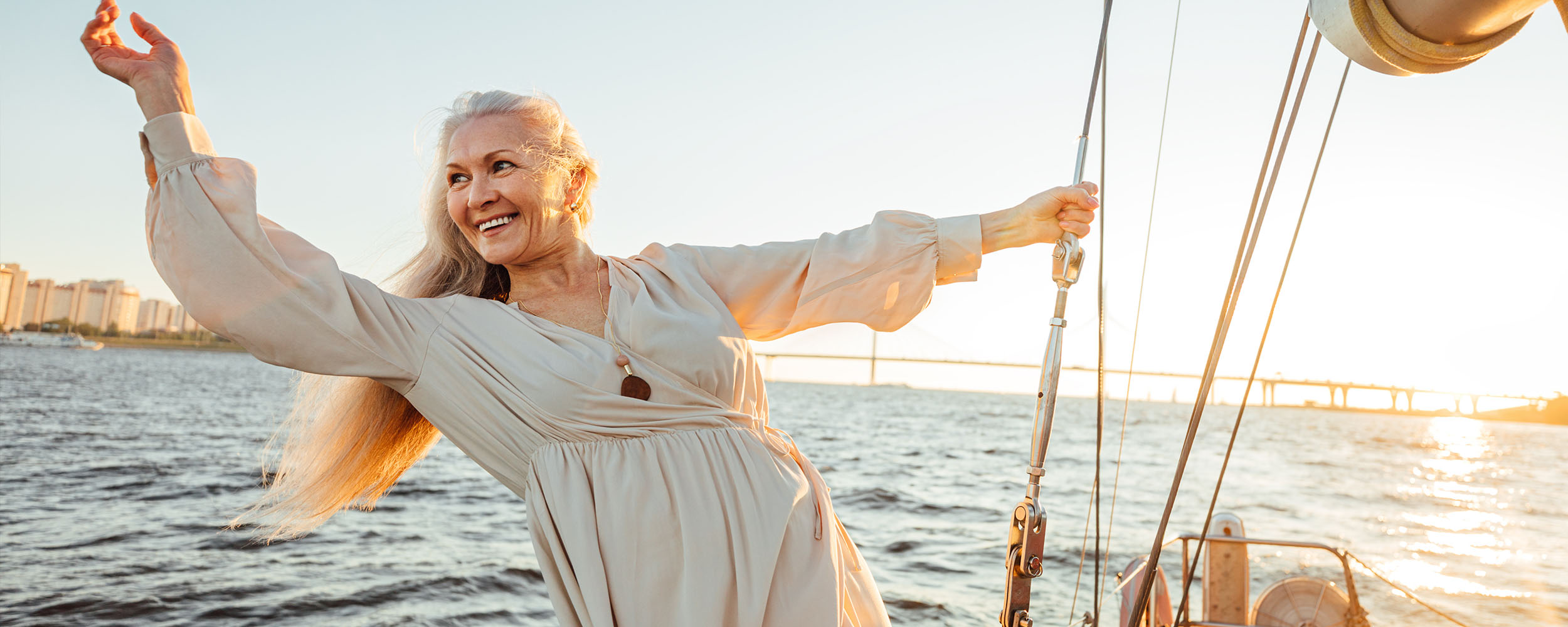An older woman standing on a sailboat, smiling.